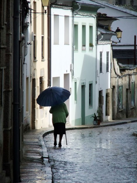 an old lady carries her umbrella on a rainy day in Mondonedo, Spain